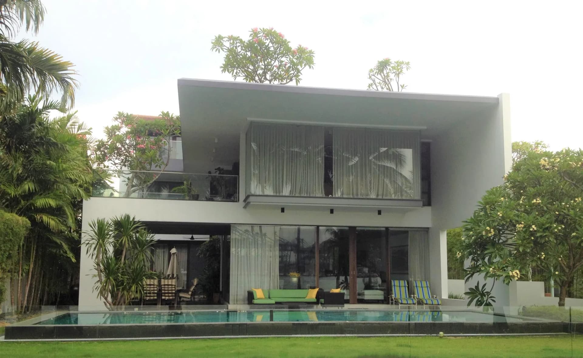 77 Ocean Drive, a white modern bungalow behind its lawn and pool